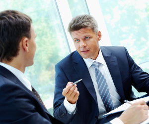 Executives in suits discussing contracts with paperwork