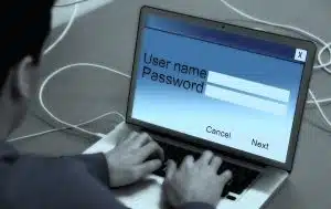 man typing in username and password on laptop